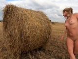 Naked exhibitionist girl in a field with straw